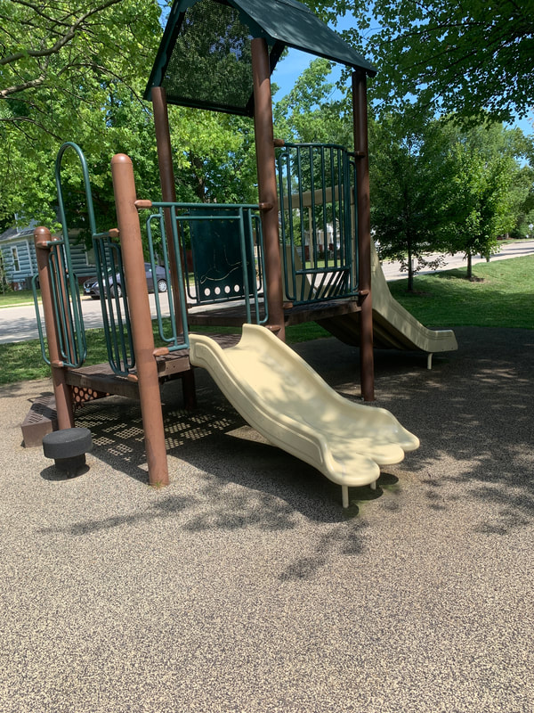 small green and brown play area with 2 slides at LeClaire Park in Edwardsville IL. Parks in Edwardsville IL
